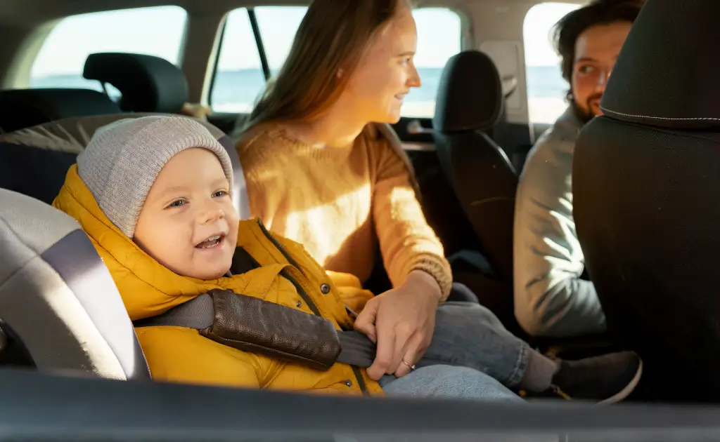A joyful toddler buckled in a convertible car seat.