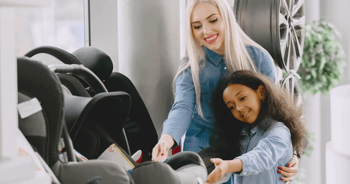 A mother and her young daughter inspecting child car seats to choose the right car seat.