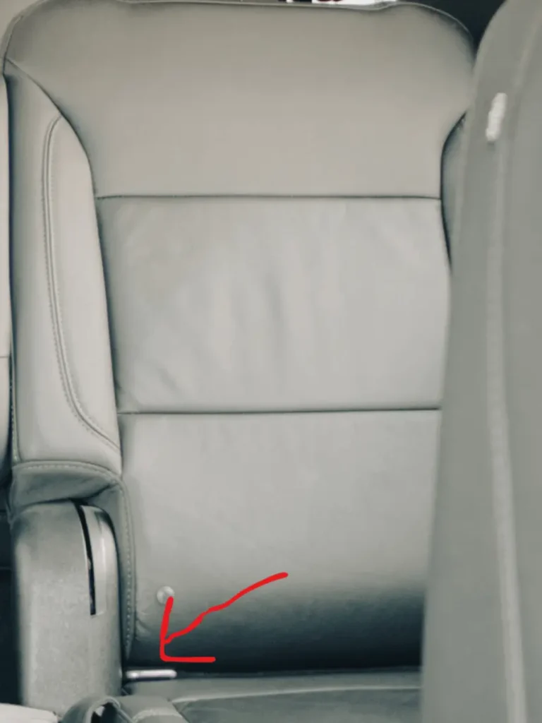 Lower anchors in a car seat highlighted with a red arrow for LATCH system installation.