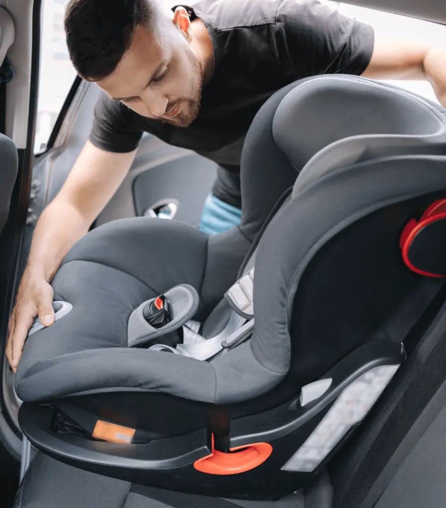 A man installing a baby car seat using the LATCH system in a car.