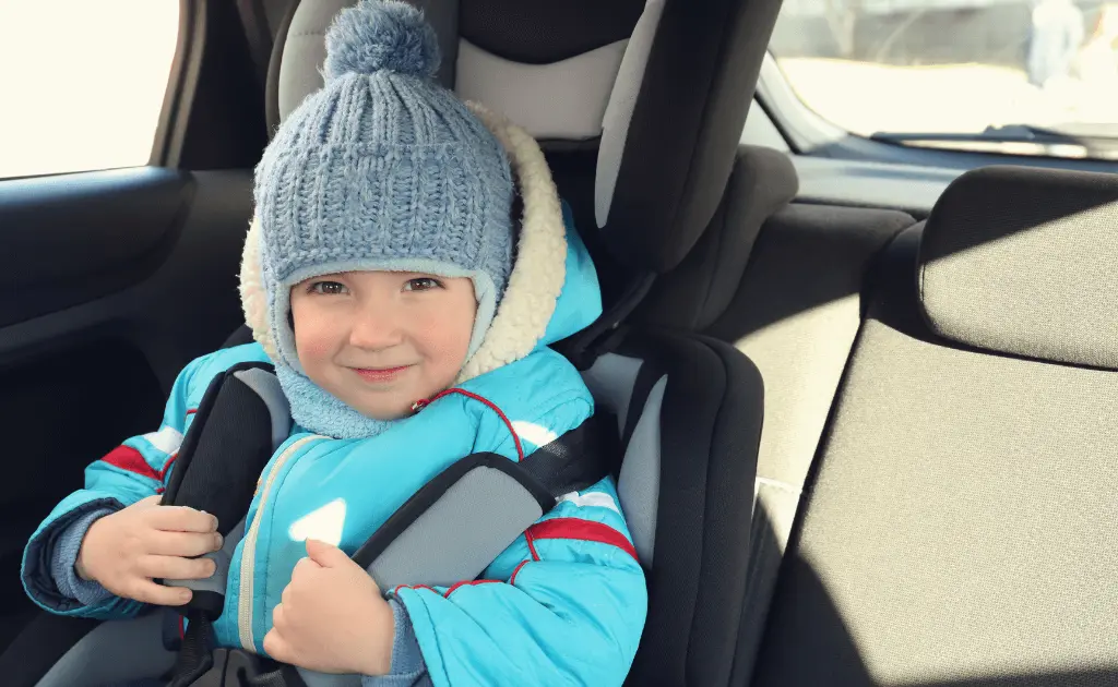 A young child sitting in a forward-facing convertible car seat inside a vehicle.