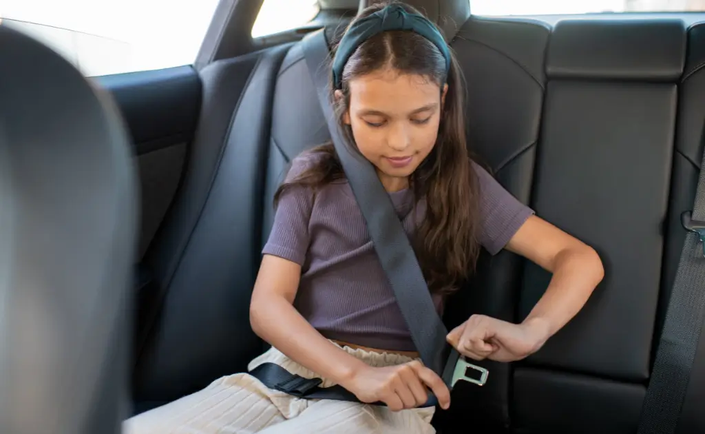 A young girl is going through 5 five-step test to get ready for a vehicle seat belt.