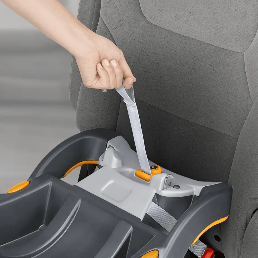 Hand pulling Chicco SuperCinch force-multiplying tightener for secure car seat installation.