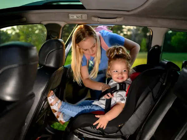 Parent securing a child safely in a baby car seat inside a family vehicle.